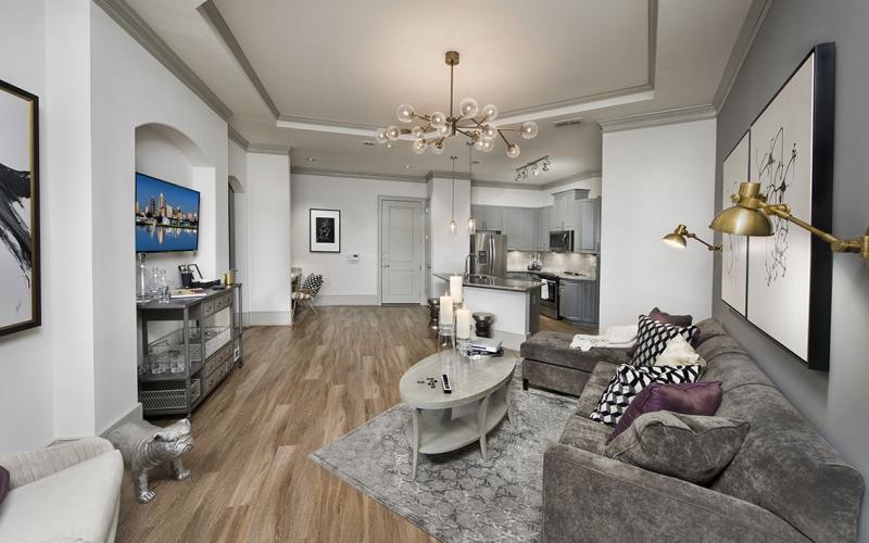 a living room with a wood floor, a couch, chairs and a tv